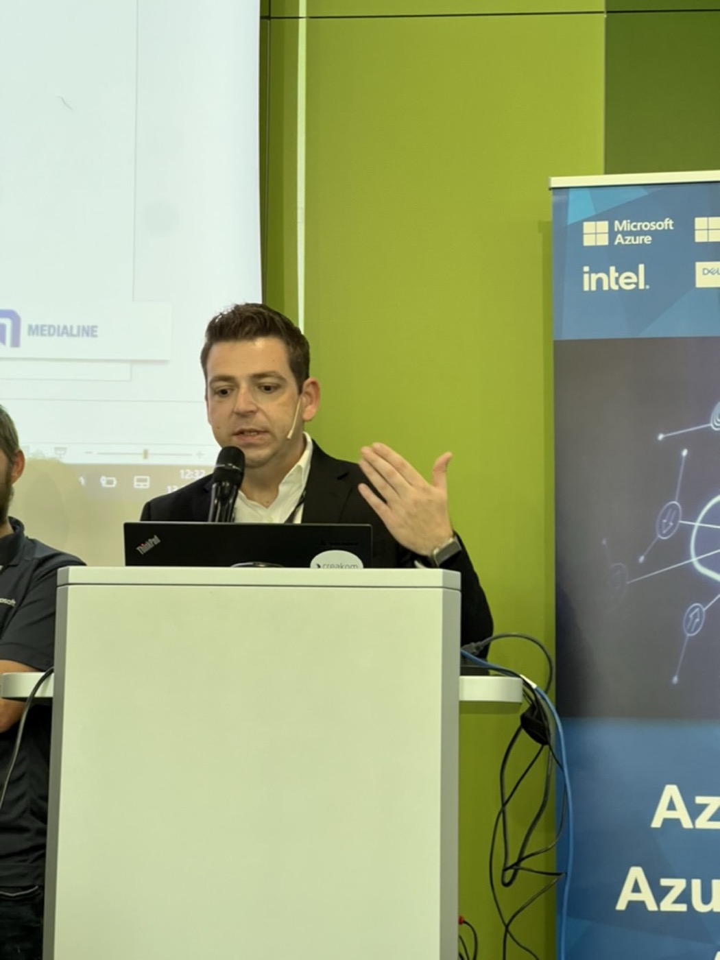 Dino Bordonaro presenting at a podium with a headset microphone, Microsoft Azure partner slide on screen