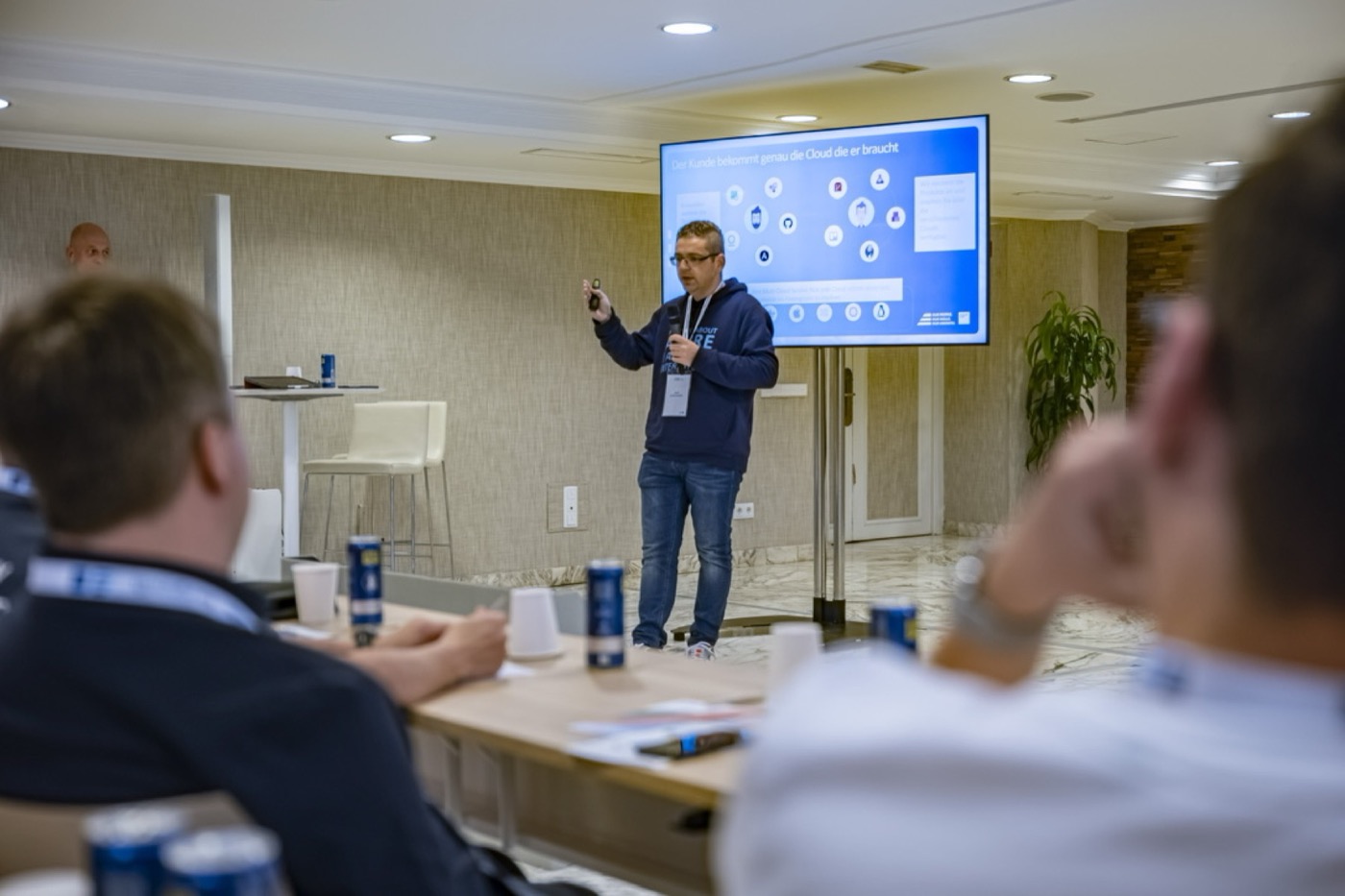 Dino Bordonaro presenting to a seated audience with microphone and clicker
